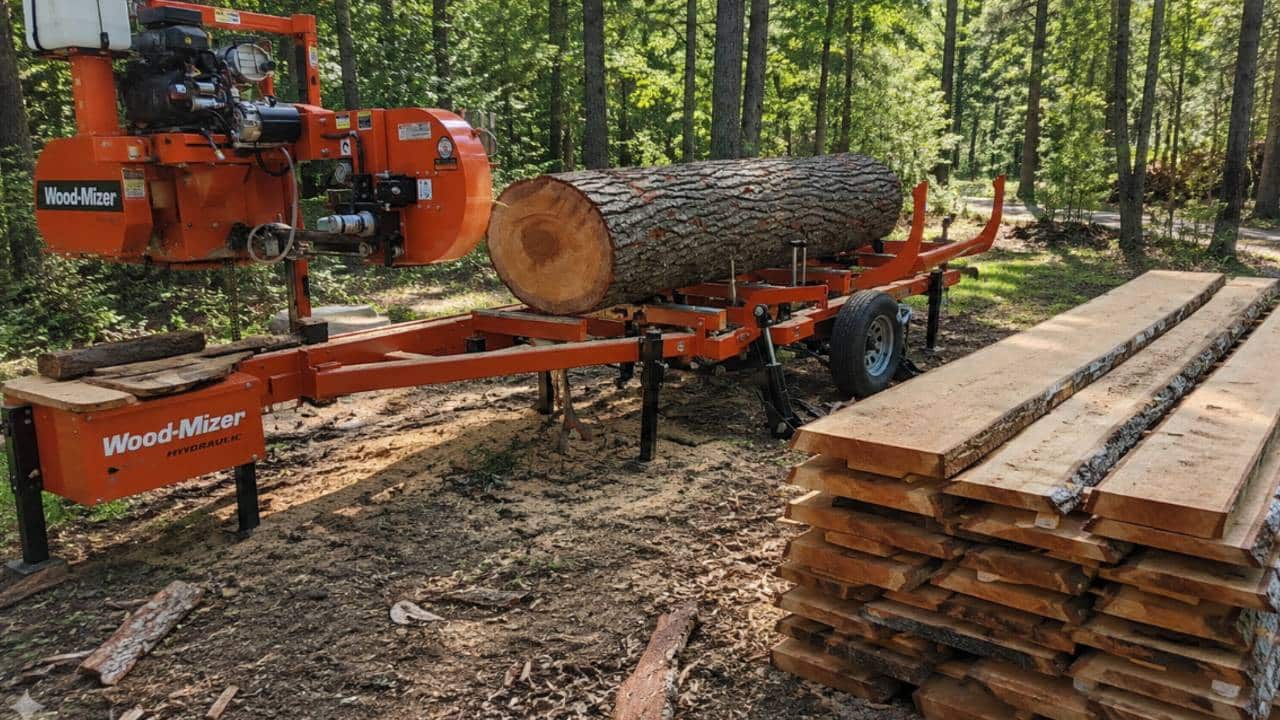 Large tree being milled on a portable sawmill with stacks of freshly cut lumber showing how much lumber one tree can produce.