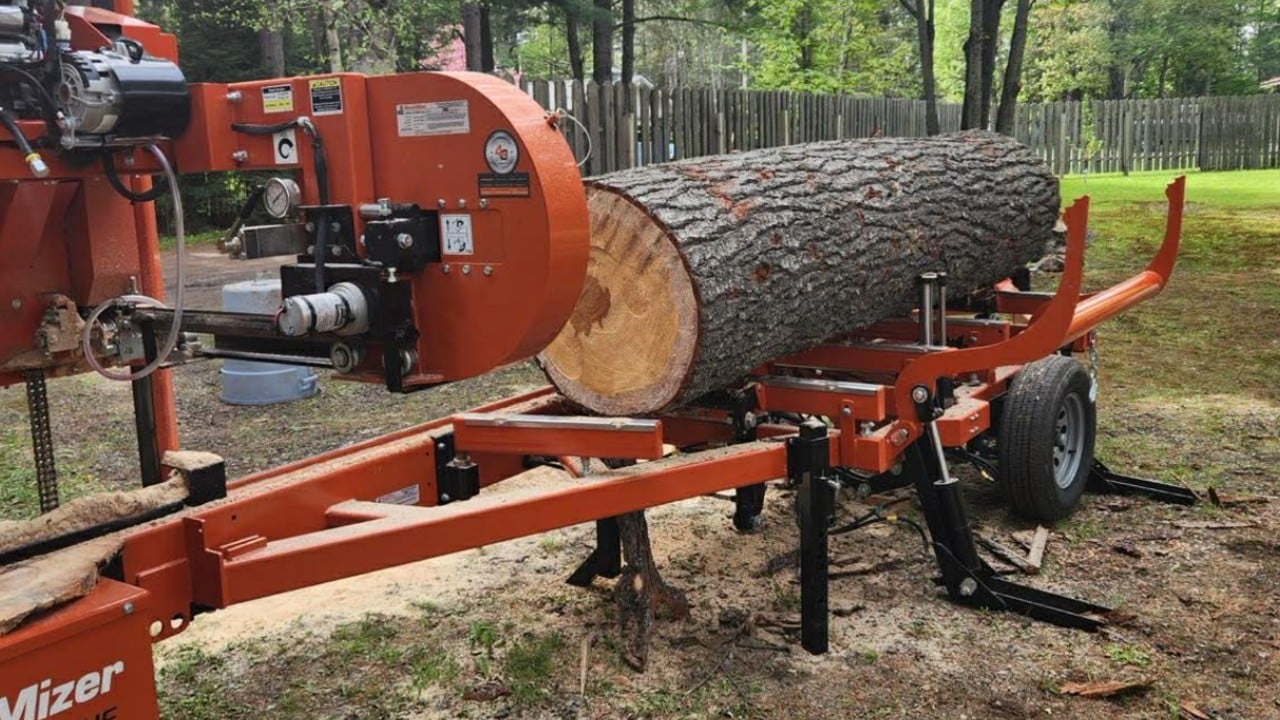 portable-sawmill Portable sawmill cutting a large hardwood log into lumber on-site with standing forest trees in the background in Michigan's Upper Peninsula